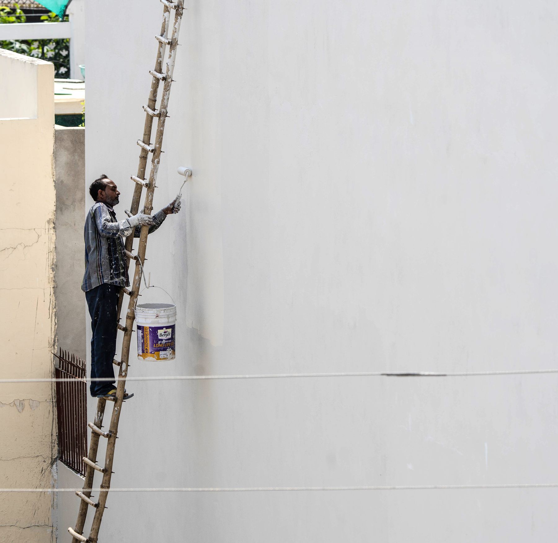Maler auf der Leiter an der Außenwand