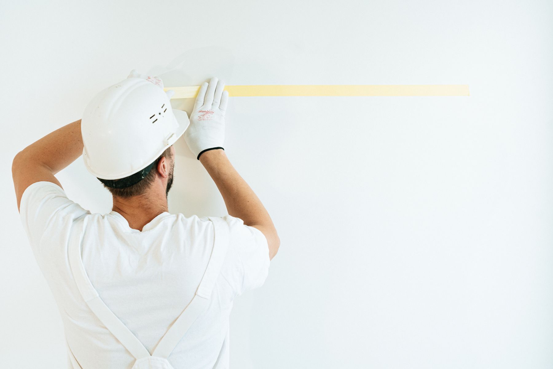 Maler klebt die Wand sauber ab